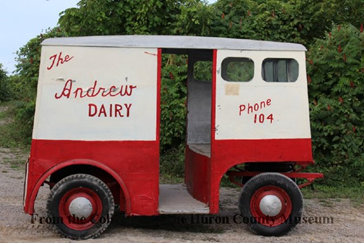 Red and white van with open sides. Text on side reads "The Andrew Dairy, Phone 104"